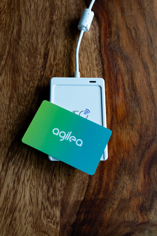 agilea Zuweisungsgerät, auf welchem eine Transponderkate von agilea im Farbverlauf zwischen Gelb und Türkis aufliegt