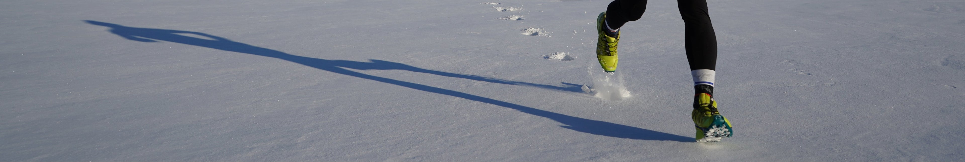 Rechteckiges Bild, auf welchem eine Person im Schnee joggt 